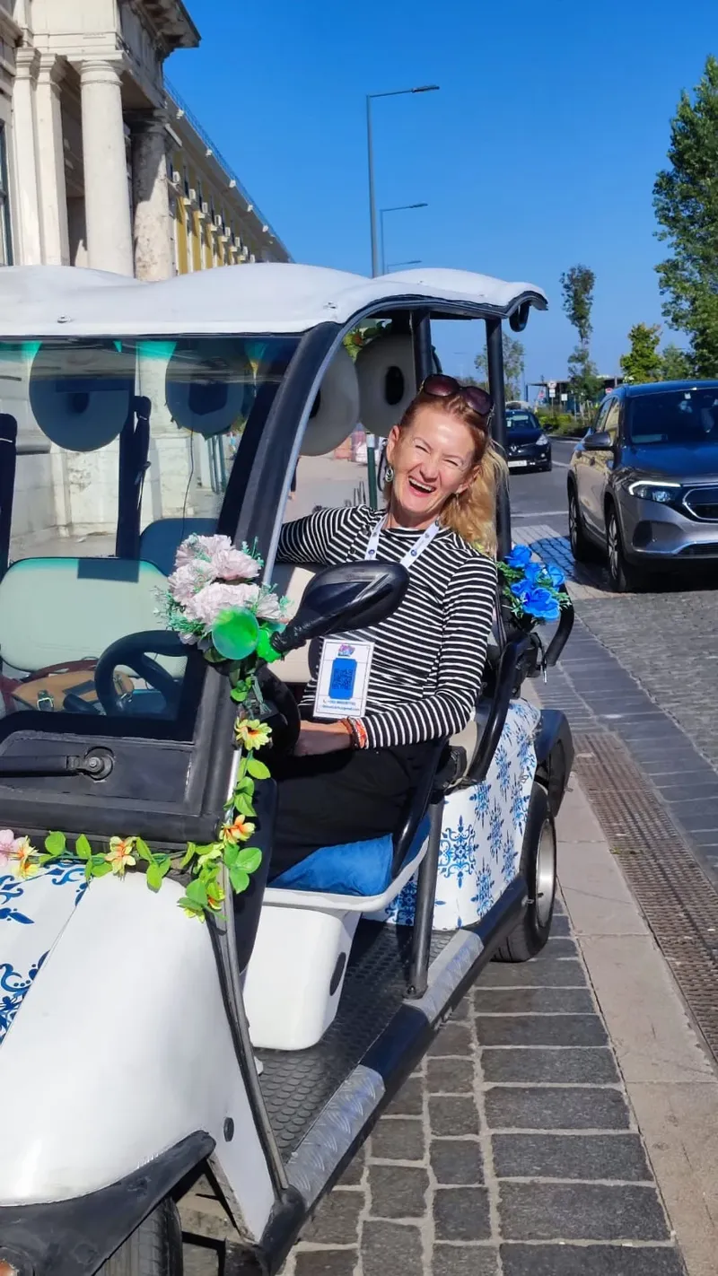 Guia certificada Susane sorrindo a bordo do tuk-tuk azul florido